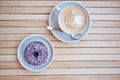 Colorful purple doughnut and cappuccino at the terrace in the cafe. Aesthetic coffee time. Top view, copy space on