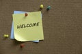 A colorful push pins and memo notes written with Welcome on a cork board Royalty Free Stock Photo