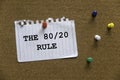 A colorful push pins and paper written with The 80/20 Rule on a cork board