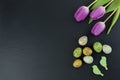 Colorful quail eggs and tulip flowers and green wooden birds on stone table. Top view with copy space Royalty Free Stock Photo