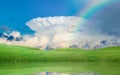 Colorful rainbow above green hills, blue sky with white incus cl Royalty Free Stock Photo