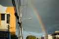 Colorful rainbow on blue sky after tropical rain on city street at dominican carnival
