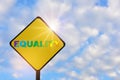 Colorful rainbow equality word written on yellow sign on beautiful blue sky with fluffy cloud background