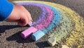 Colorful rainbow kid drawing with colourful pastel sidewalk chalks on the pavement