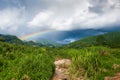 Colorful rainbow over tropical mountain valley in the rain, scenic landscape green forest and stream in countryside Royalty Free Stock Photo