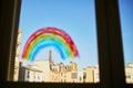 Colorful rainbow painted on window glass in Parisian apartment, Eiffel tower is seen in the background