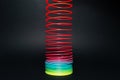 Colorful rainbow spiral toy on black background.