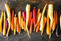 Colorful raw rainbow carrots arranged in a row over a black stone background Royalty Free Stock Photo