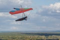 Colorful red hang glider wing soars over fields and forests