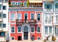 Colorful red mansion with arched windows and beautiful balconies with flowers. Classic architecture buildings facades