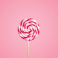 Colorful red and white lollipop candy on pastel pink background