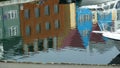 Colorful reflection in harbour water, houses, brown facade center, sailboat lower right