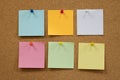 Colorful reminder sticky notes push pins on cork board.