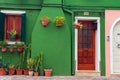 Colorful residential houses in Burano island, Venice, Italy. Street with green facade building