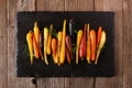 Colorful roasted rainbow carrots arranged in a row on a slate serving platter against a rustic wood background