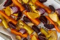 Colorful roasted vegetables on tray with parchment. Mix of carrots, beets, turnips, rutabaga, onions. Vegetarianism, veganism,