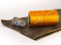 Colorful roll of thread on a piece of leather with a needle and a thimble. Royalty Free Stock Photo