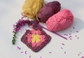 Colorful round crochet pattern with flowers on white table. Granny squares made of soft pink organic yarn.