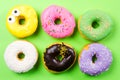 Colorful round donuts on green background. Flat lay, top view. Royalty Free Stock Photo