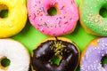 Colorful round donuts on green background. Flat lay, top view. Royalty Free Stock Photo