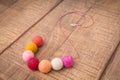 Colorful round wool felt beads necklace handmade with white, pink, red, orange and peachy color beads on a wood table Royalty Free Stock Photo