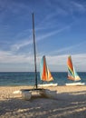 Colorful sail catamarans on the beach.