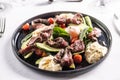 Colorful salad with flank steak filling the dark plate on a restaurant table Royalty Free Stock Photo