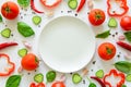 Colorful salad ingredients pattern made of tomatoes, pepper, chili, garlic, cucumber slices, basil and empty plate on white backgr Royalty Free Stock Photo