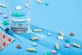 Colorful scattered tablets, water glass, blister with medical pills, multivitamins Royalty Free Stock Photo