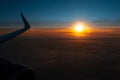 Colorful scenic view of beautiful dark sunset, cloudy sky and airplane wing with engine, through window of the aircraft. Royalty Free Stock Photo