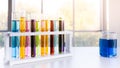 Colorful science test tube in plastic rack with blue water in beaker on white top table Royalty Free Stock Photo