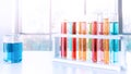 Colorful science test tube in plastic rack with blue water in beaker on white top table