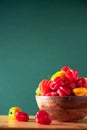 Colorful scotch bonnet chili peppers in wooden bowl over green background. Copy space. Royalty Free Stock Photo