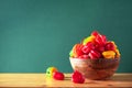 Colorful scotch bonnet chili peppers in wooden bowl over green background. Copy space. Royalty Free Stock Photo