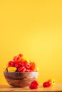 Colorful scotch bonnet chili peppers in wooden bowl over orange background. Copy space. Royalty Free Stock Photo