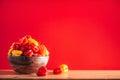 Colorful scotch bonnet chili peppers in wooden bowl over red background. Copy space. Royalty Free Stock Photo