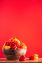 Colorful scotch bonnet chili peppers in wooden bowl over red background. Copy space. Royalty Free Stock Photo