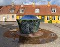 Colorful sculpture and fountain with reflections and traditional houses in the background