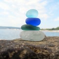 Colorful sea glass pyramid on beach rock with seascape background. Seaglass stack beach combing