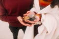 Colorful sea pebbles on couple's hands close up. Happy young couple at the winter beach wrapped in white blanket Royalty Free Stock Photo