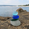 Colorful seaglass stack on beach rock with seascape background. Beachcombing