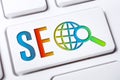 Colorful SEO Search Engine Optimization Button With Globe And Magnifying Glass On A White Keyboard, Business Marketing