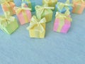 Colorful series of square gift boxes are randomly placed on a blue-green watercolor texture background, copy space.