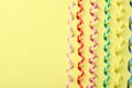 Colorful serpentine streamers on yellow background, flat lay. Space for text