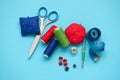 Colorful sewing accessories with threads, scissors, pins, fabric, buttons and sewing tape on blue background. Top view. Flat lay