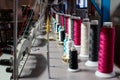 Colorful sewing thread rolls sitting on top of industrial embroidering machines