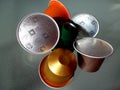 Colorful shiny metallic aluminum coffee capsules on glass surface