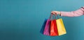 Colorful shopping bags in female hand on blue background. Copy space, Female hand holding many colorful shopping bags on blue Royalty Free Stock Photo