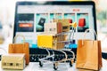 Colorful shopping cart boxes near open laptop. Technologically advanced digital shopping experience. AI Image