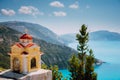 Colorful shrine Proskinitari on pedestal. Amazing sea view to Greece coastline in the background